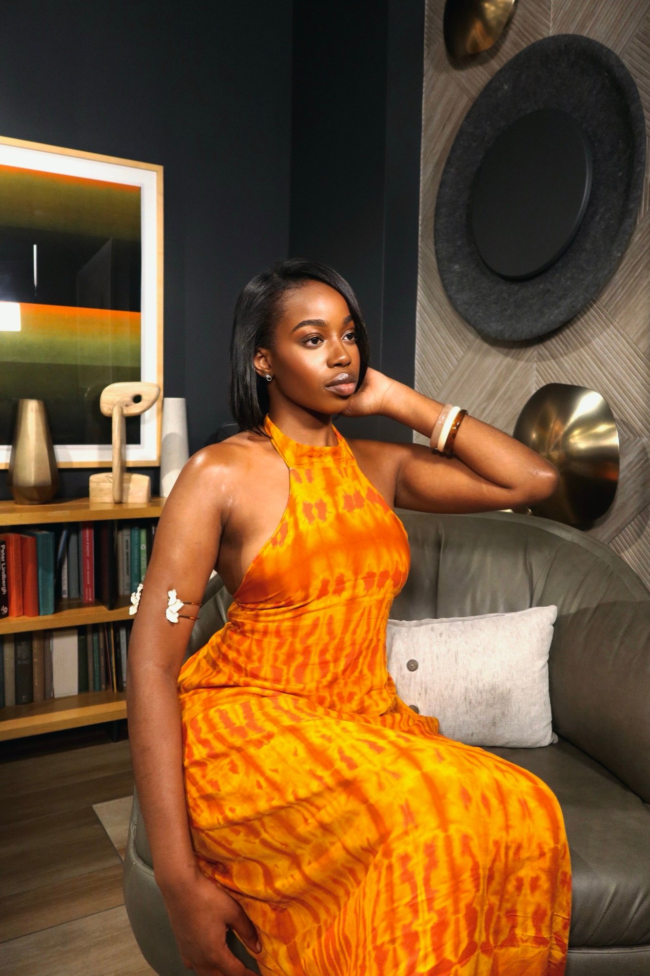 Model seated in the orange tie-dye Belle de Dos halter dress with a hand behind her head